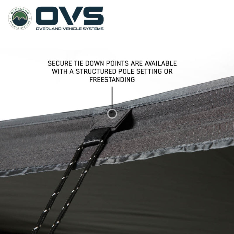 Image of a close-up of an OVS XD Nomadic 270 LTE awning showing a reinforced tie-down point with attached guy line on black fabric, displayed in detail on a white background.
