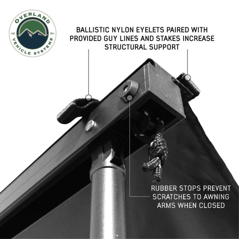 Image of the Nomadic Awning showing a close-up of the ballistic nylon eyelets with a guy line, highlighting the structural support. Rubber stops are also visible to prevent scratches on the awning arms when closed. The awning fabric is black