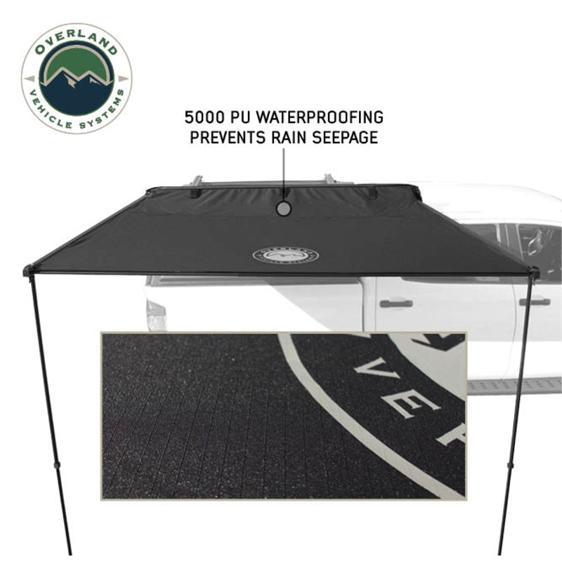 Image of the Nomadic Awning in a rolled-up state, showing a close-up of a large, heavy-duty Velcro strap used for storage. The awning has light grey fabric
