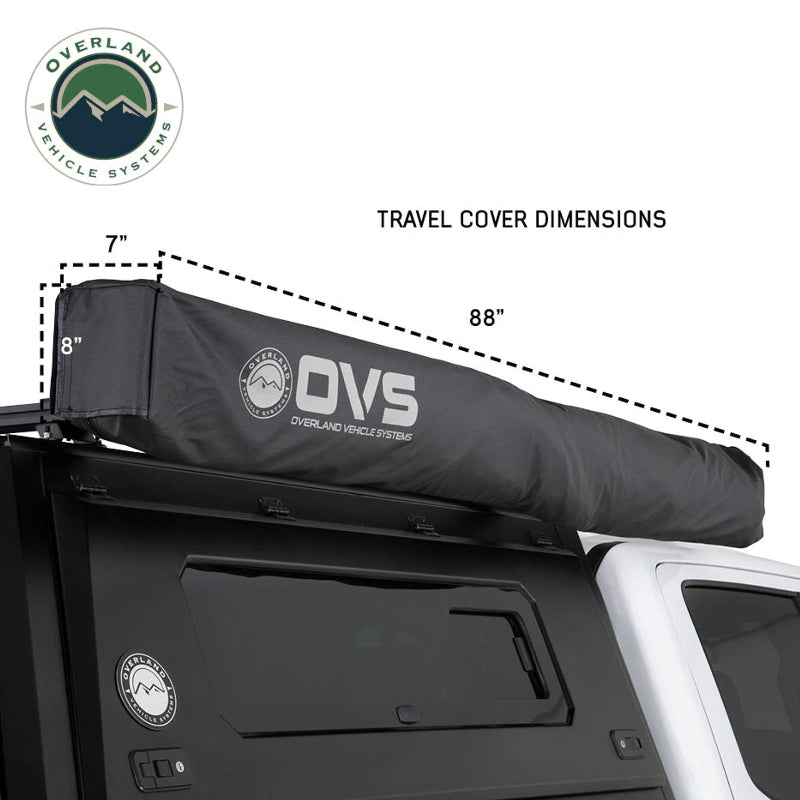 Side view of a white pickup truck with the OVS Nomadic Awning fully stowed in its travel cover. The black travel cover, with the OVS logo, has dimensions overlaid to show its compact size when not in use