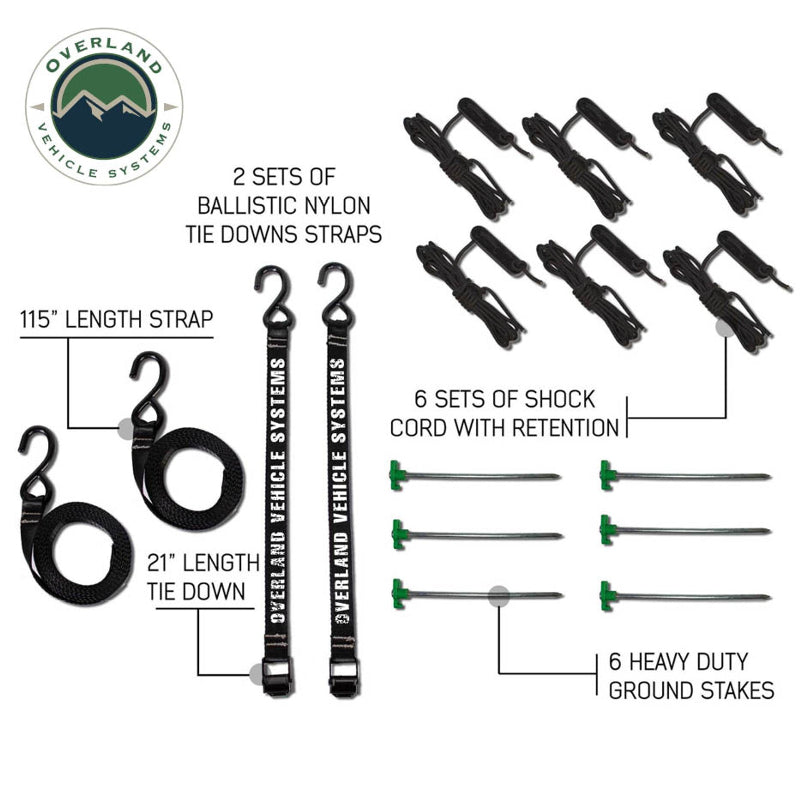 Top-down product shot of the OVS Nomadic Awning's included accessories. The image displays two ballistic nylon tie-down straps with dimensions, six shock cord sets, and six heavy-duty ground stakes, all laid out on a white background with descriptive text