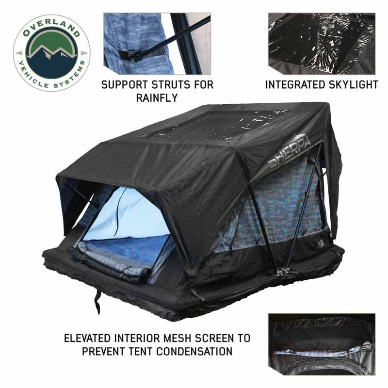 Image showcasing an Overland Vehicle Systems Sherpa Roof Top Tent, fully deployed with a black exterior and blue interior, highlighting features like support struts for the rainfly, an integrated skylight, and an elevated interior mesh screen to prevent condensation. The tent is shown at an angle on a white background