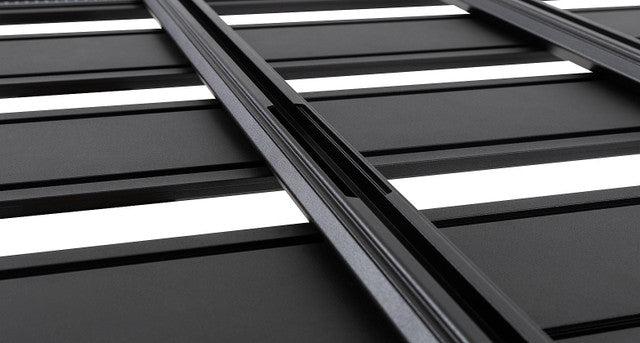 Image of Rhino-Rack roof rack, black aluminum frame with slatted design and white inlays, close-up angled view of the grooves on white background