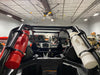 Red RollPaX container and a white RollPaX container mounted to the sides of a vehicle, with the interior of a garage visible in the background, angled rear view.