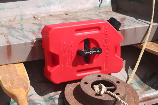 Image of RotopaX 1 Gallon Gasoline fuel container with black mount attached, red can resting on metal boat deck with rope and hardware, angled outdoor view.