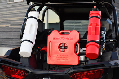 Three Rotopax fuel containers—one white 1.5-gallon, one red 2-gallon, and one red 1.5-gallon—mounted on the rear of an off-road vehicle, showcasing secure storage for extra fuel.