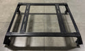 Image of Thors Lightning truck bed rack frame in black powder-coated steel with crossbars, angled top and side view on concrete floor background.
