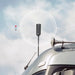 Image of a black antenna or sensor mounted on the roof of a truck or vehicle, with a white target overlay centered on it, and three colored dots (red, gray, gray) to the left, set against a cloudy sky